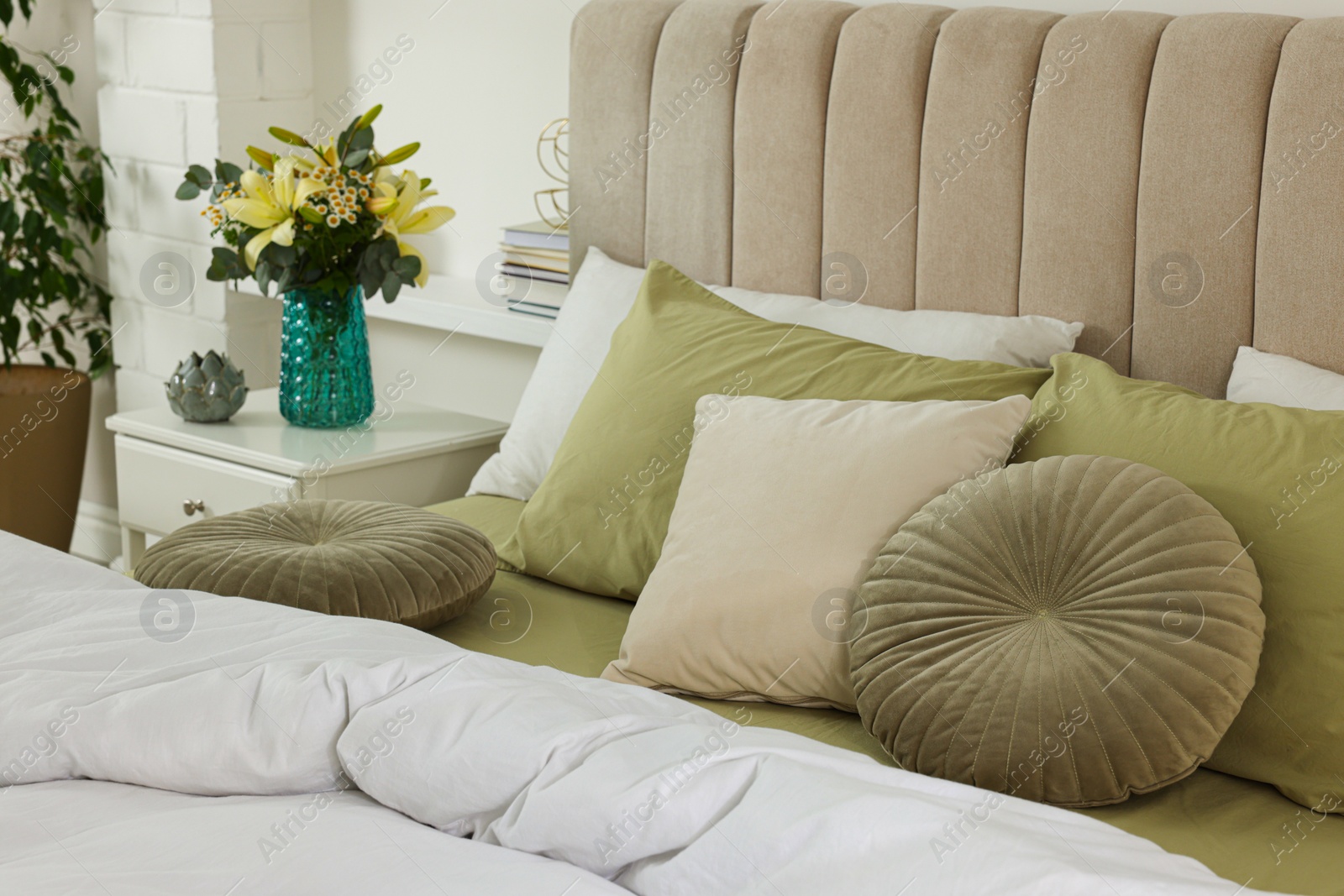 Photo of Bouquet of beautiful flowers and decor on nightstand in bedroom