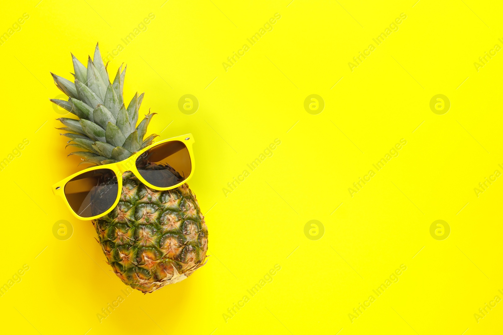 Photo of Pineapple and sunglasses on color background, top view with space for text. Beach accessories