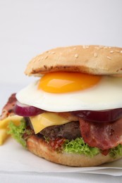 Delicious burger with fried egg on white tiled table, closeup