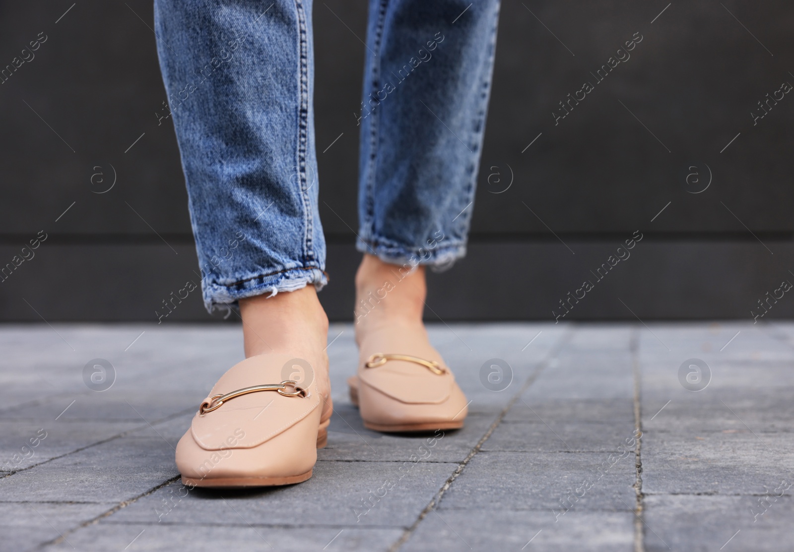 Photo of Woman in blue jeans and fashionable slippers walking on city street, closeup. Space for text