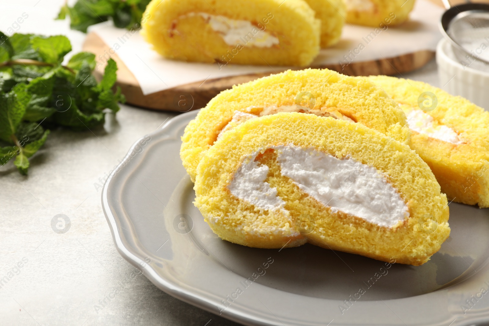 Photo of Delicious cake roll with cream filling on grey table, closeup