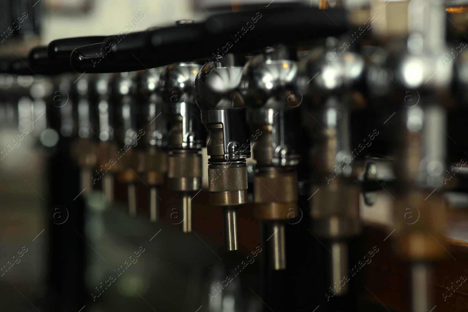 Photo of New modern beer taps in pub, closeup. Professional bar equipment