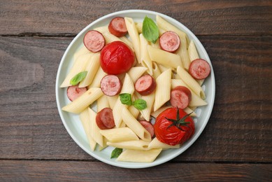 Photo of Tasty pasta with smoked sausage, tomatoes and basil on wooden table, top view