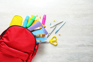 Photo of Flat lay composition with backpack, school stationery and space for text on light background