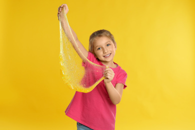 Photo of Little girl with slime on yellow background