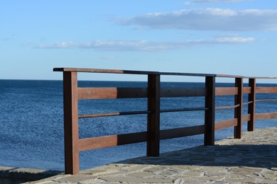 Wooden railing near sea outdoors on sunny day