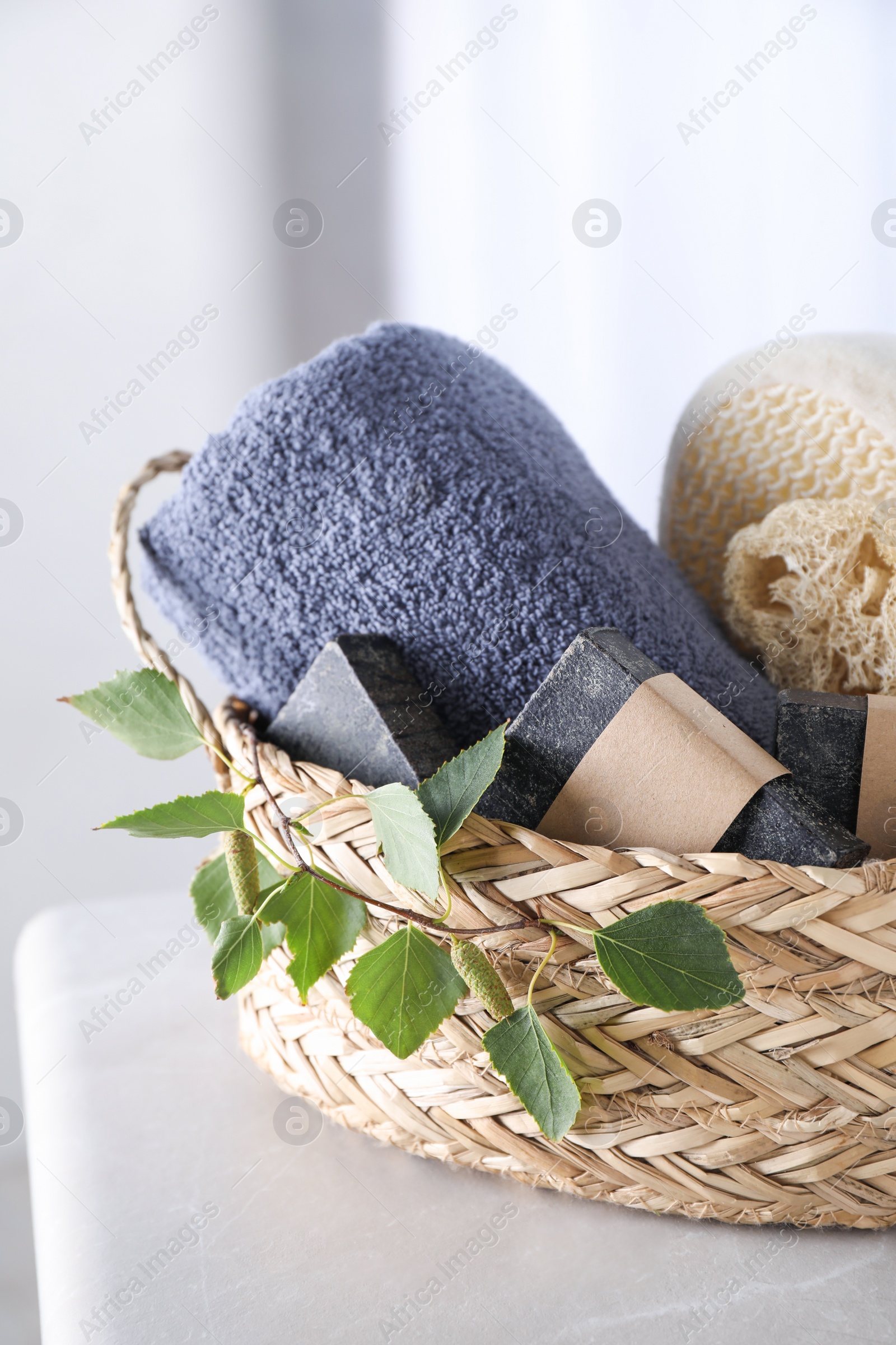 Photo of Natural tar soap in wicker basket on white table, closeup