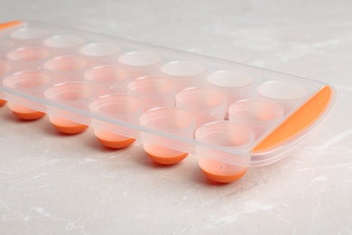 Photo of Empty ice cube tray on grey table, closeup
