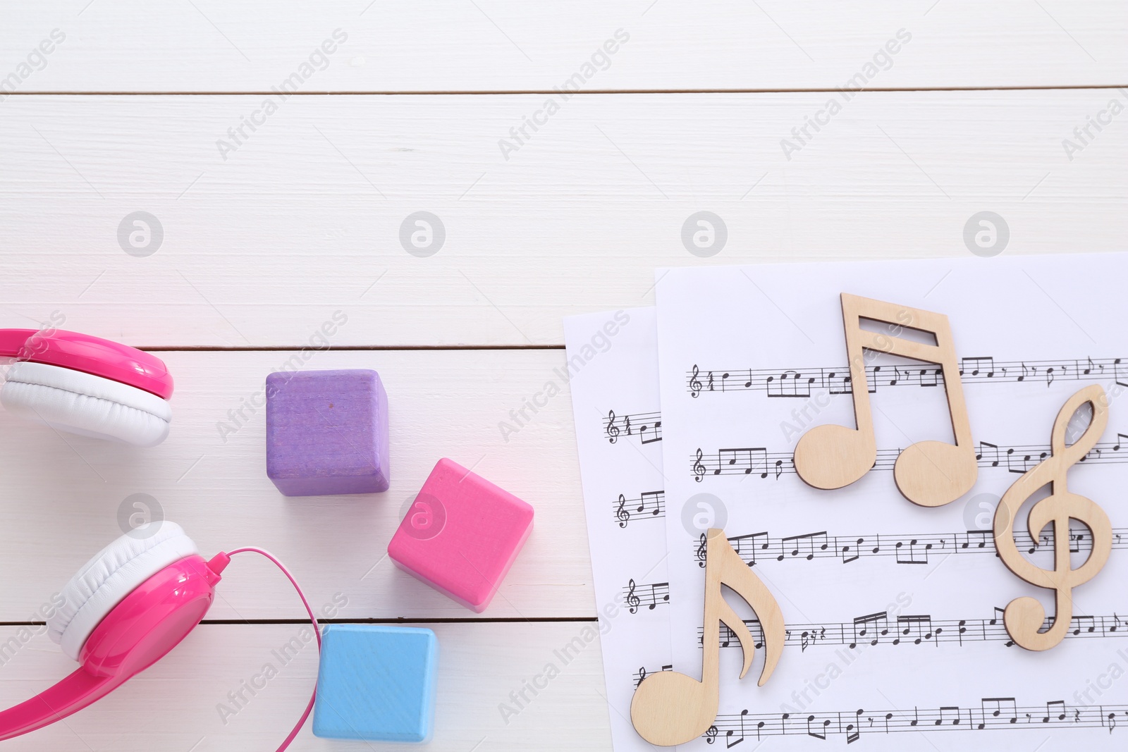 Photo of Notes, music sheets, headphones and cubes on white wooden table, flat lay with space for text. Baby song concept