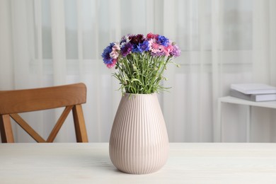 Photo of Bouquet of beautiful cornflowers in vase on white wooden table at home
