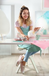 Young woman with cup of cotton candy dessert at table in room