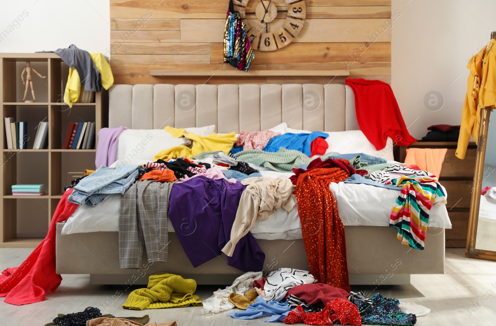 Photo of Pile of clothes on bed in messy room. Fast fashion concept