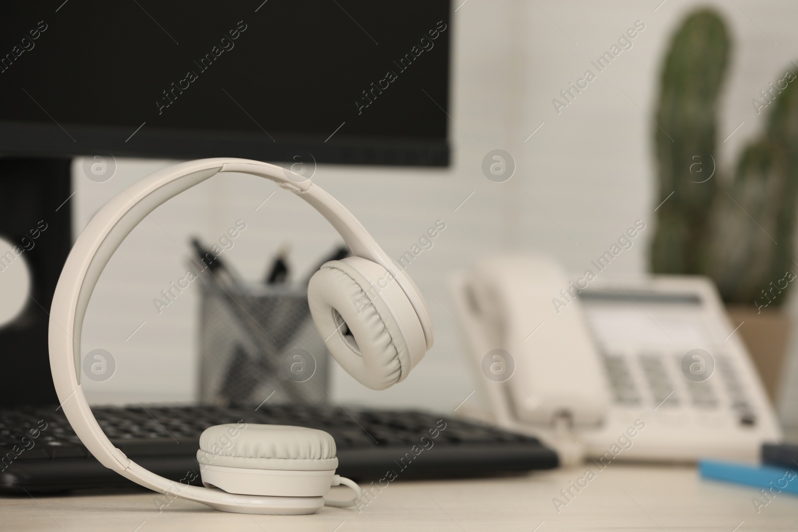 Photo of Modern headphones, desktop telephone and computer on table indoors, space for text