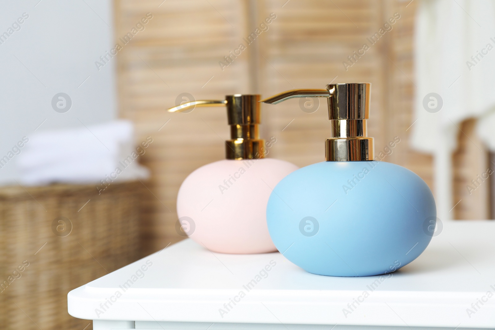 Photo of Stylish soap dispensers on table against blurred background. Space for text