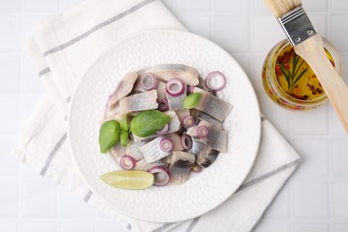 Photo of Plate with tasty fish, onion and marinade on light tiled table, flat lay