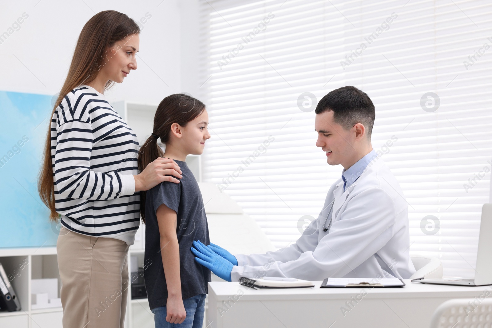 Photo of Gastroenterologist examining girl with stomach ache in clinic