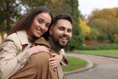 Photo of Romantic young couple spending time together in autumn park, space for text