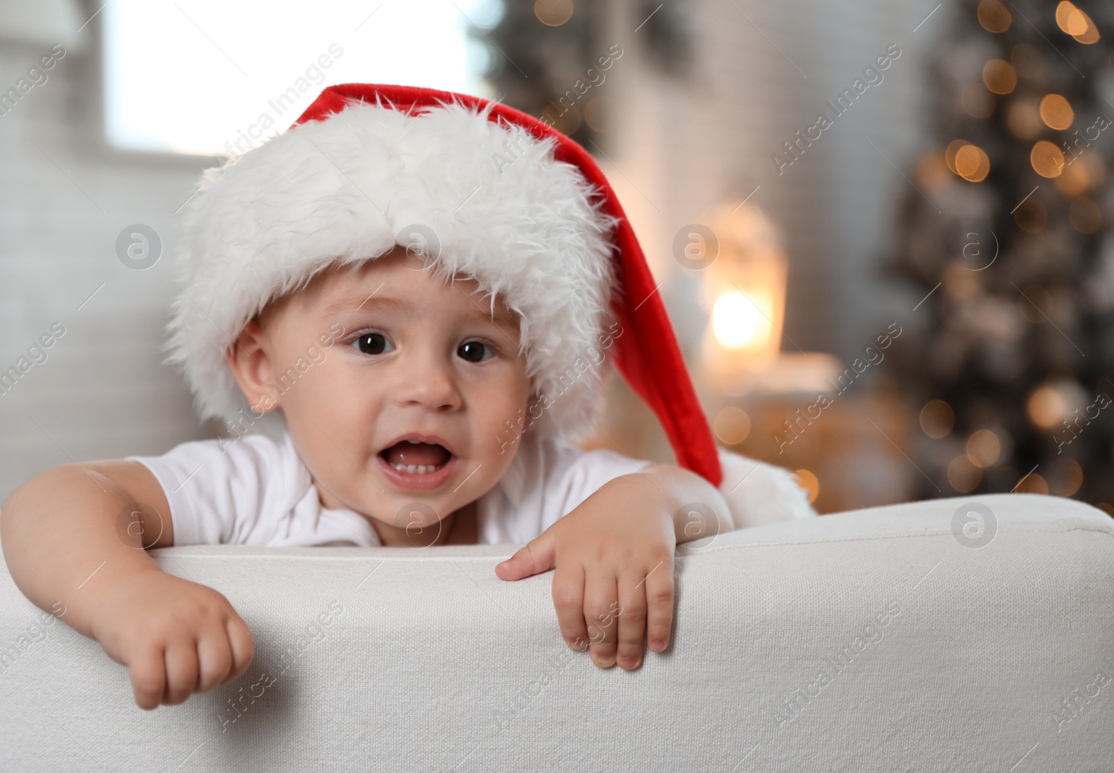 Image of Cute little baby wearing Santa hat at home. Christmas celebration