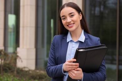 Photo of Real estate agent with leather portfolio outdoors. Space for text