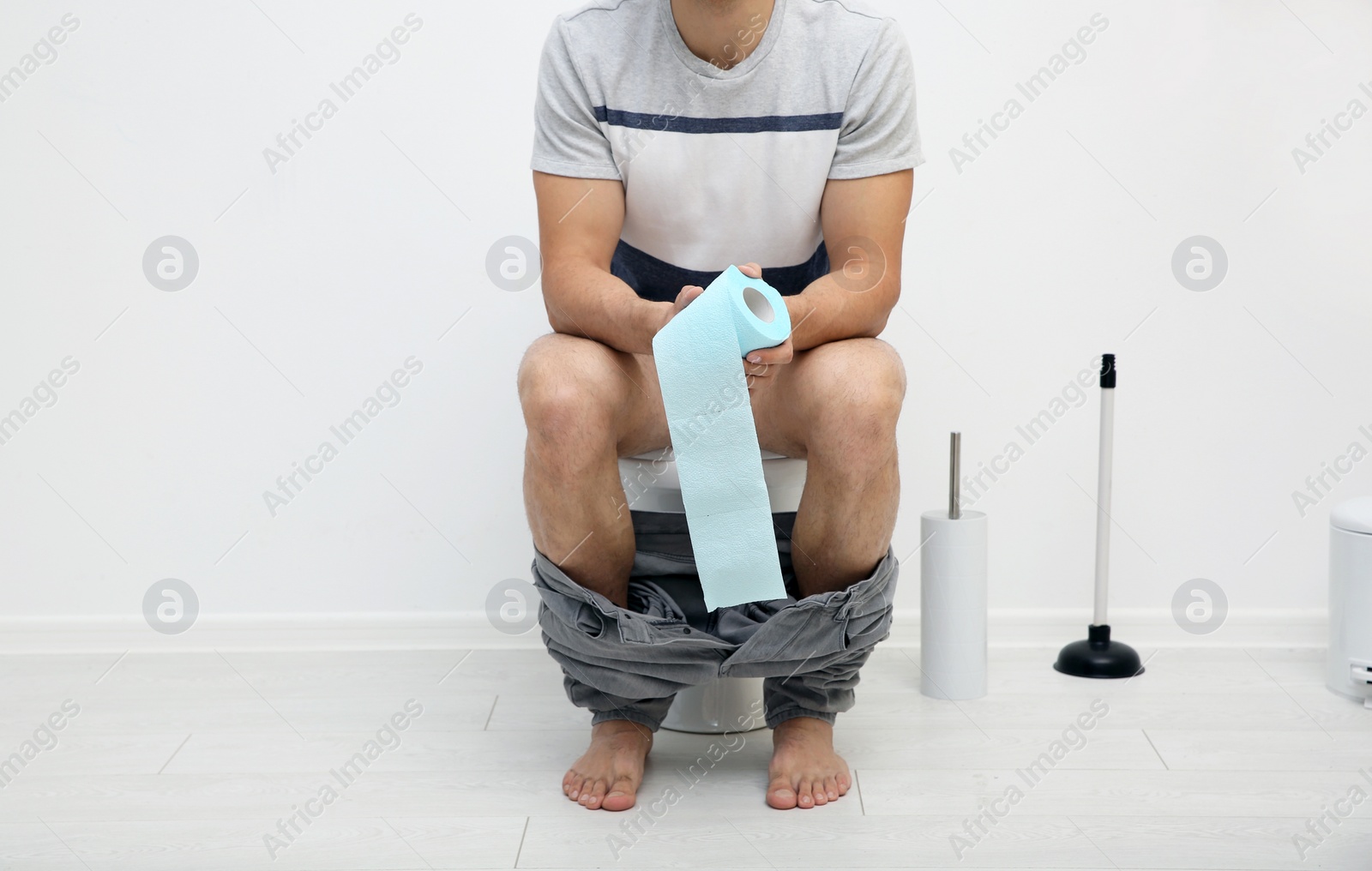 Photo of Young man with paper roll in bathroom