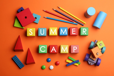 Photo of Colorful wooden cubes with phrase SUMMER CAMP on orange background, flat lay