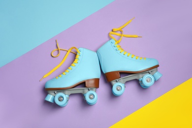 Pair of stylish quad roller skates on color background, top view