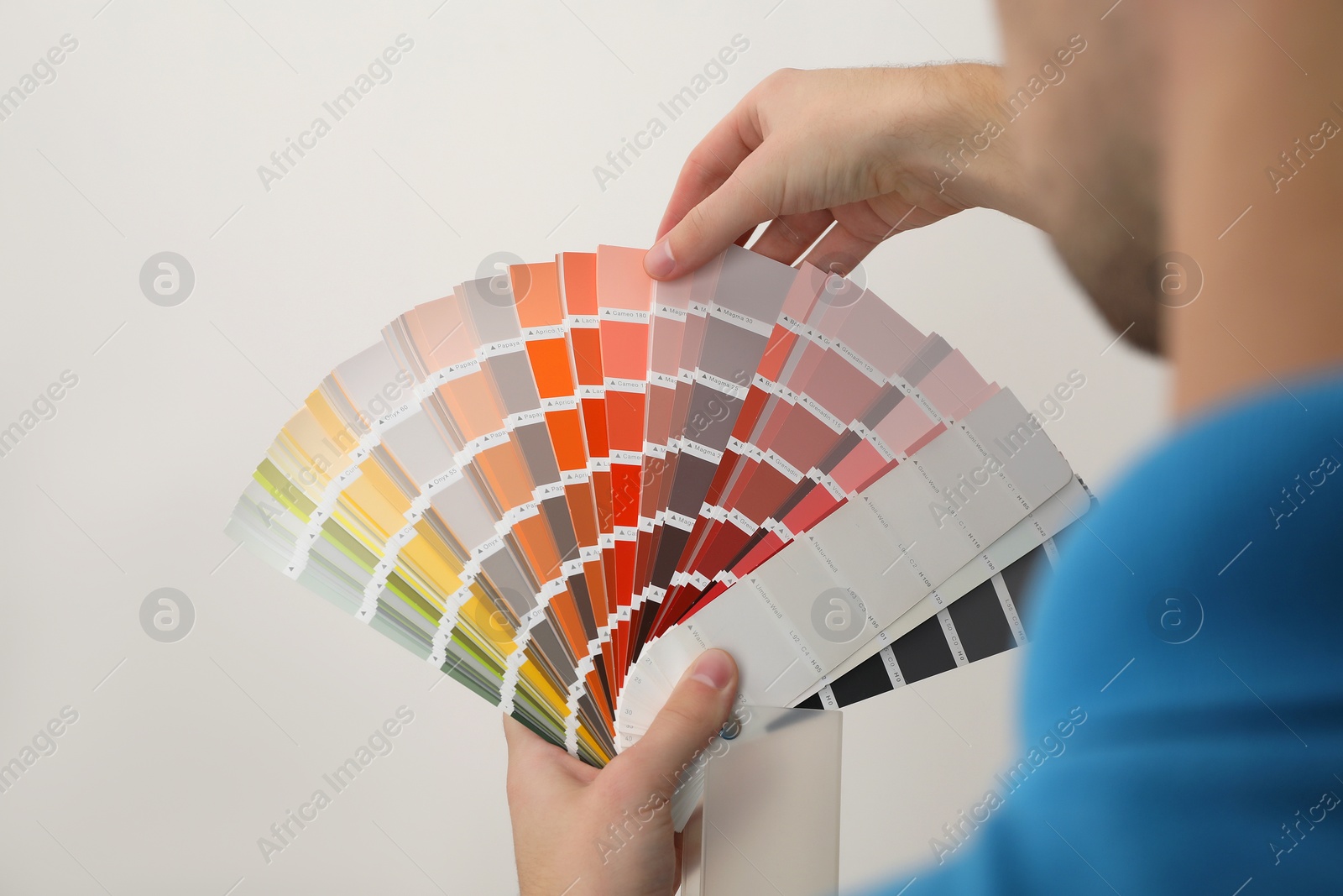 Photo of Man with palette choosing color for painting wall indoors, closeup. Interior design