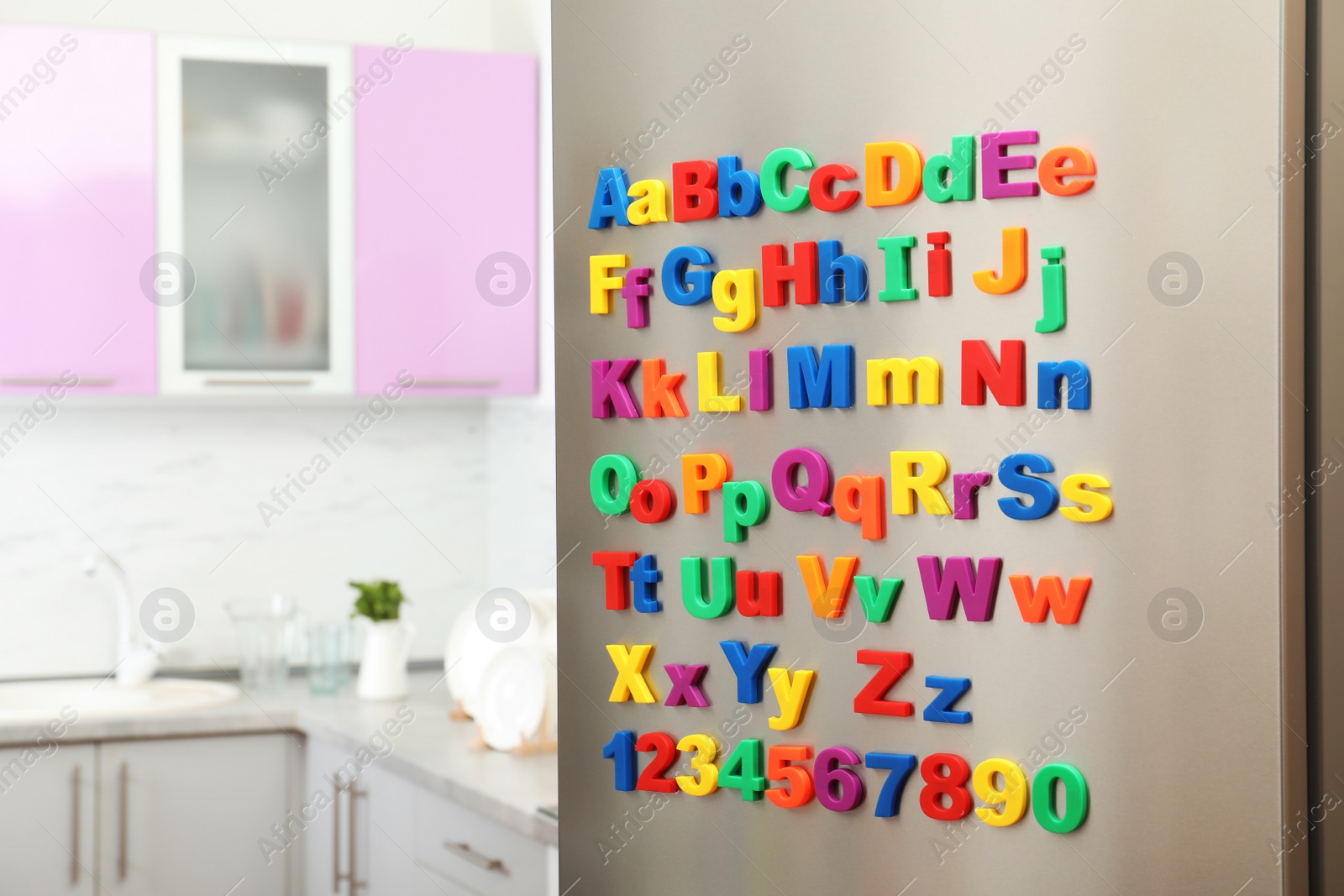 Photo of Refrigerator door with colorful magnetic letters and numbers in kitchen. Space for text