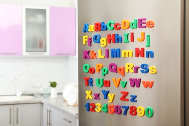 Photo of Refrigerator door with colorful magnetic letters and numbers in kitchen. Space for text