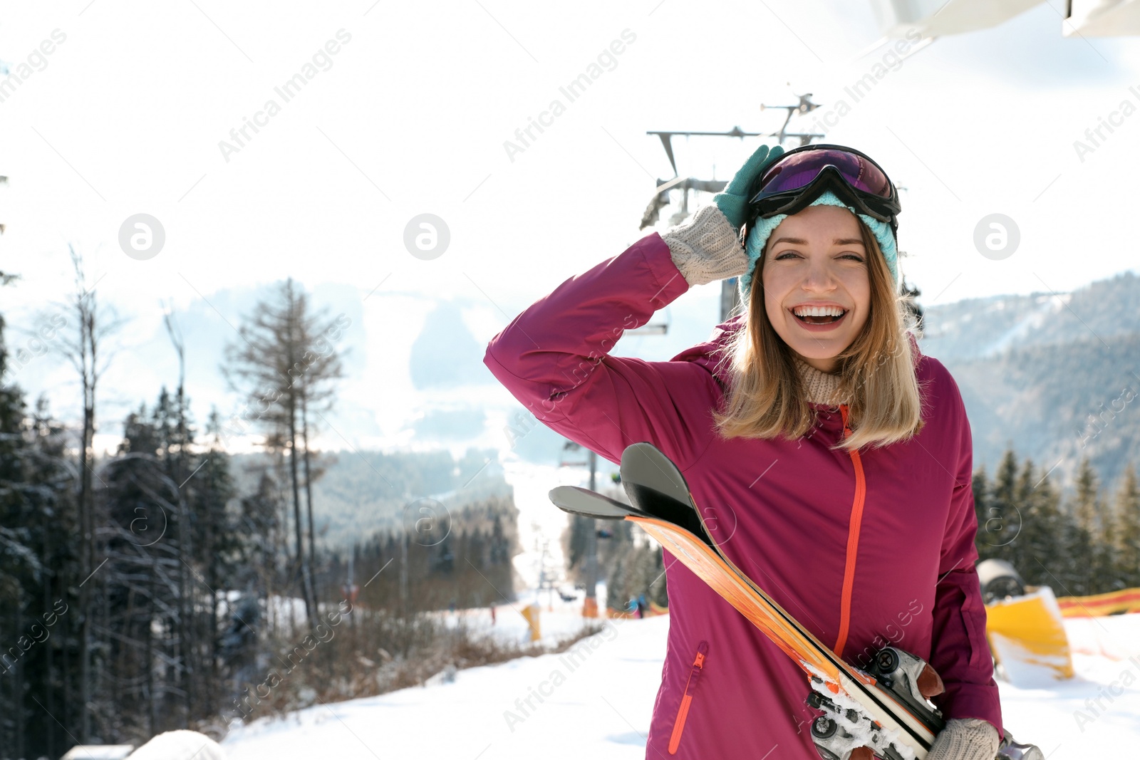 Photo of Happy young woman with ski equipment near chairlift at mountain resort, space for text. Winter vacation