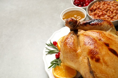 Photo of Traditional Thanksgiving day feast with delicious cooked turkey and other seasonal dishes served on grey table, closeup. Space for text