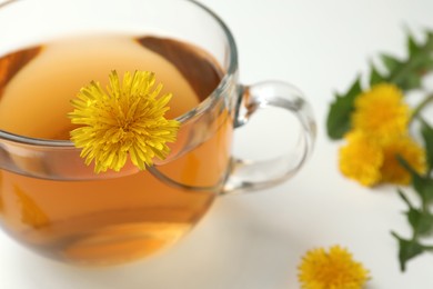 Photo of Delicious fresh tea with dandelion flowers on white table, closeup