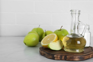 Photo of Vinegar and fresh fruits on white marble table, space for text. Eco friendly natural detergents