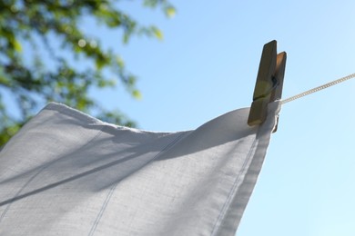 Photo of Washing line with clean laundry and clothespin outdoors, closeup