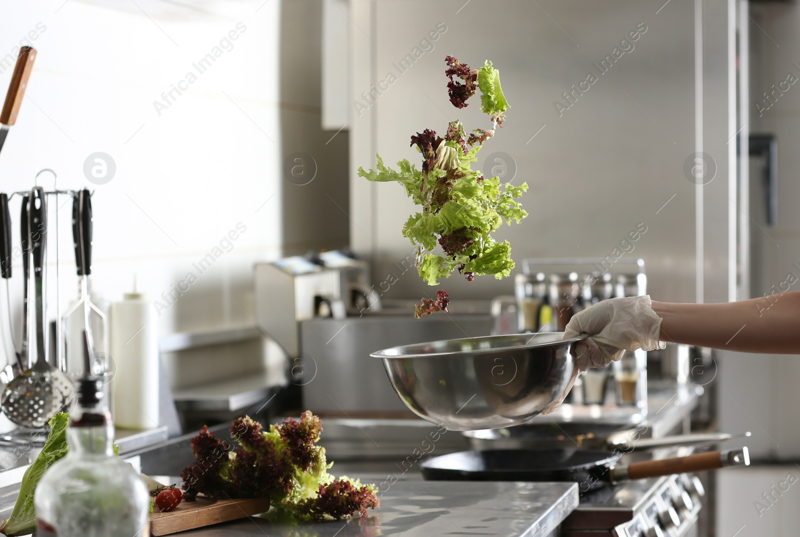 Photo of Woman cooking tasty salad with lettuce in restaurant kitchen