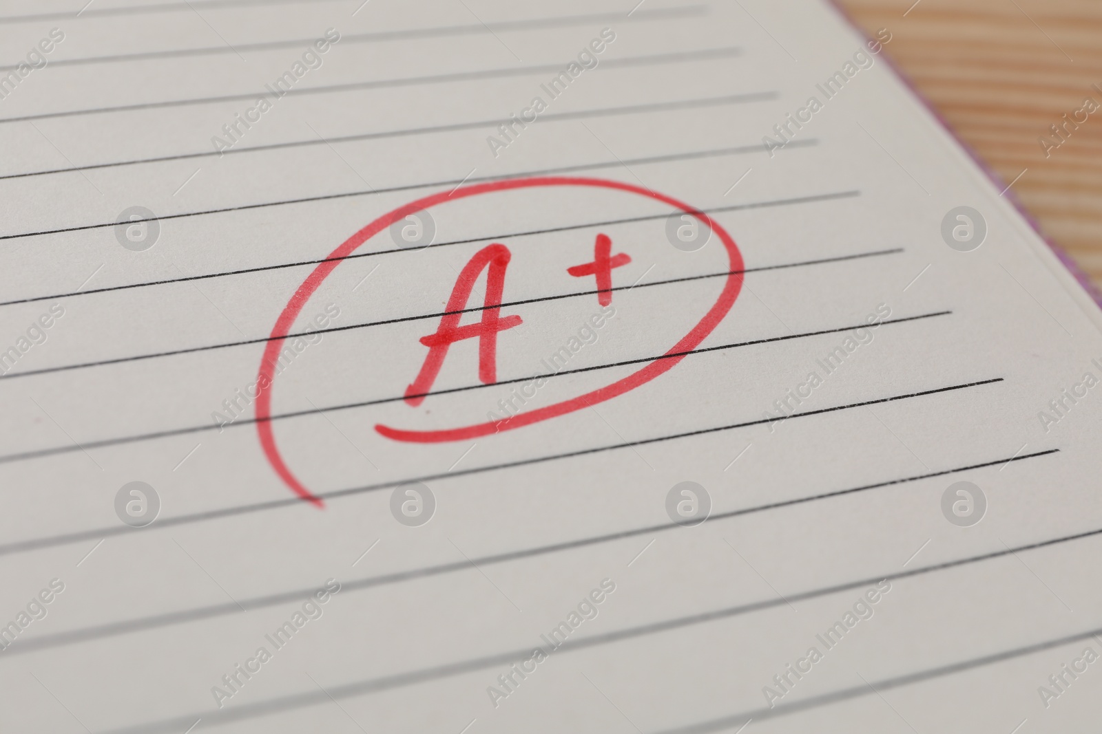 Photo of School grade. Red letter A with plus symbol on notebook paper, closeup