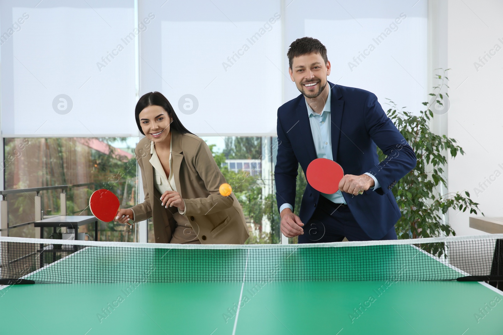 Photo of Business people playing ping pong in office