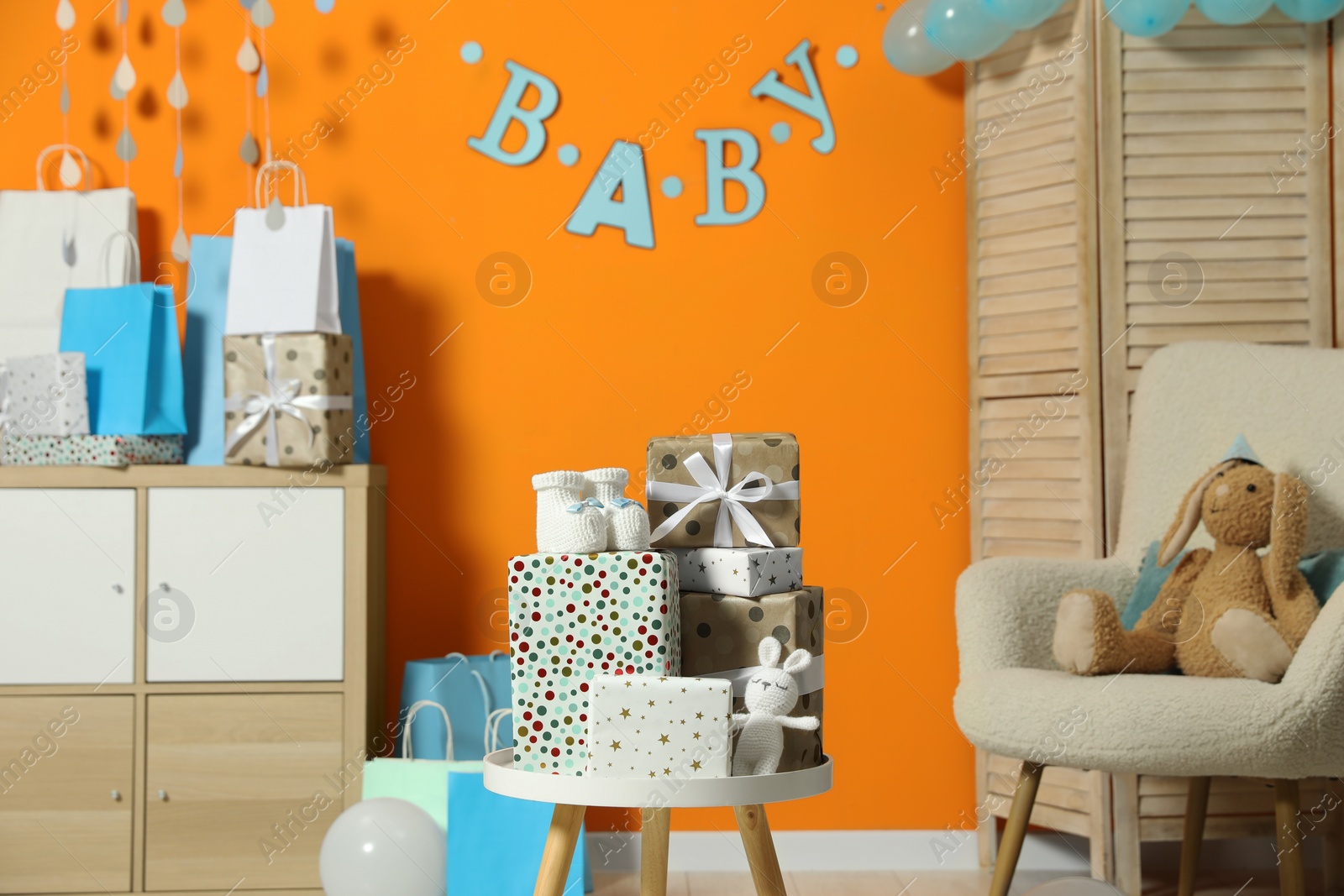 Photo of Baby shower party. Festive decor, gift boxes, booties and toys in stylish room