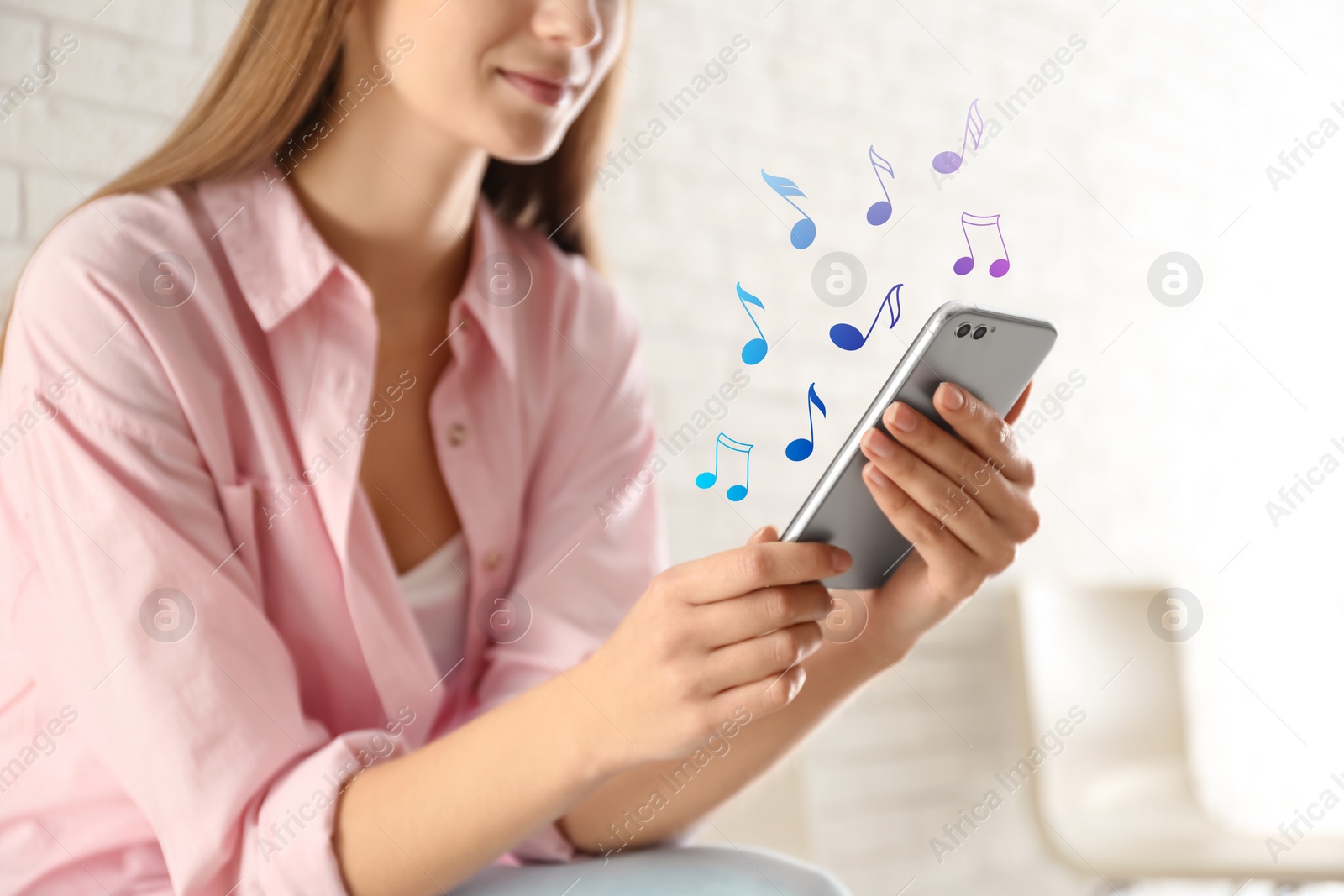 Image of Woman listening to music on mobile phone indoors, closeup. Music notes illustrations over gadget