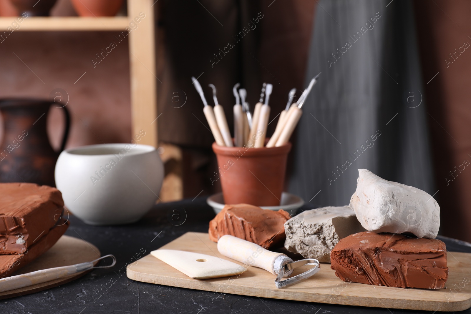 Photo of Clay and set of modeling tools on table in workshop