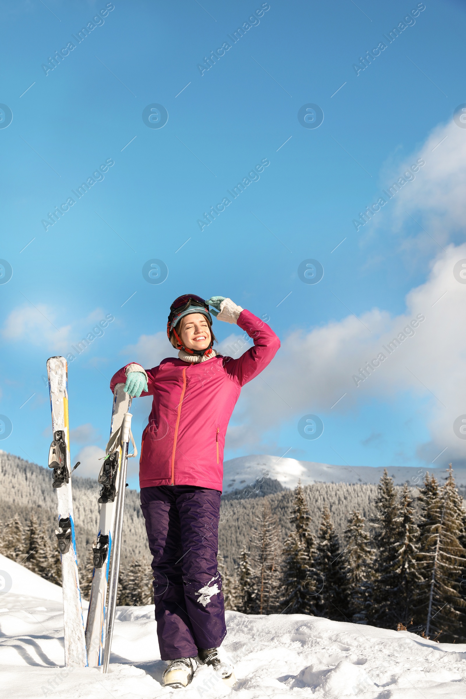 Photo of Happy young woman with ski equipment spending winter vacation in mountains