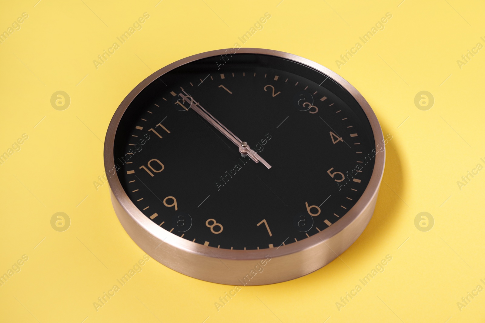 Photo of Stylish round clock on yellow background. Interior element