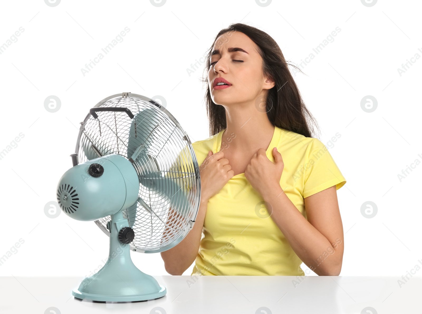 Photo of Woman suffering from heat in front of fan on white background. Summer season