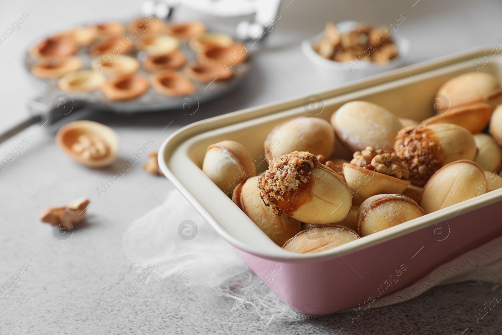 Photo of Freshly baked delicious walnut shaped cookies on light grey table, closeup. Space for text