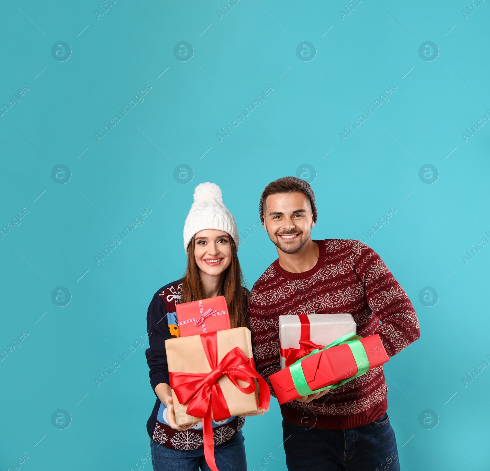 Photo of Couple in Christmas sweaters with gift boxes on blue background