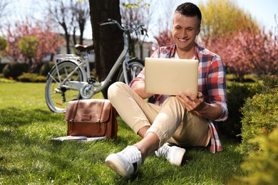 Man working with laptop on grass in park