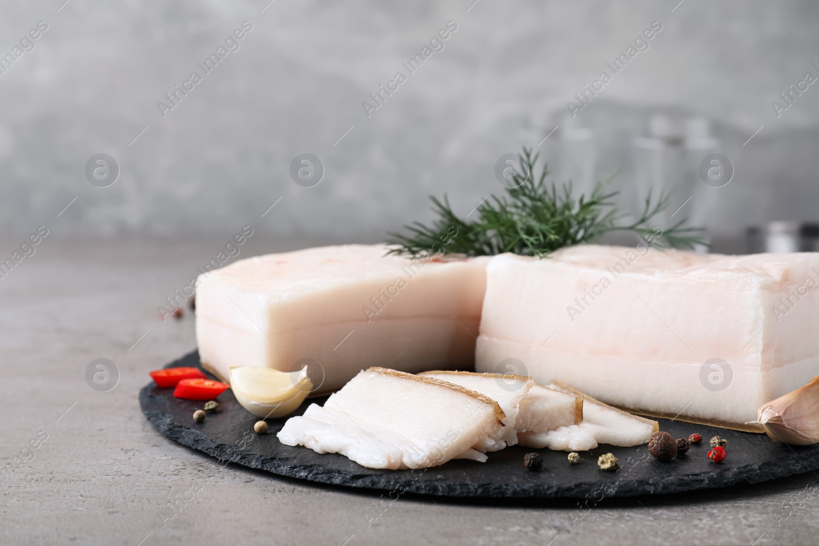 Photo of Pork fatback with spices served on grey table