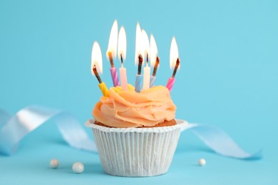 Photo of Tasty birthday cupcake with many candles on light blue background