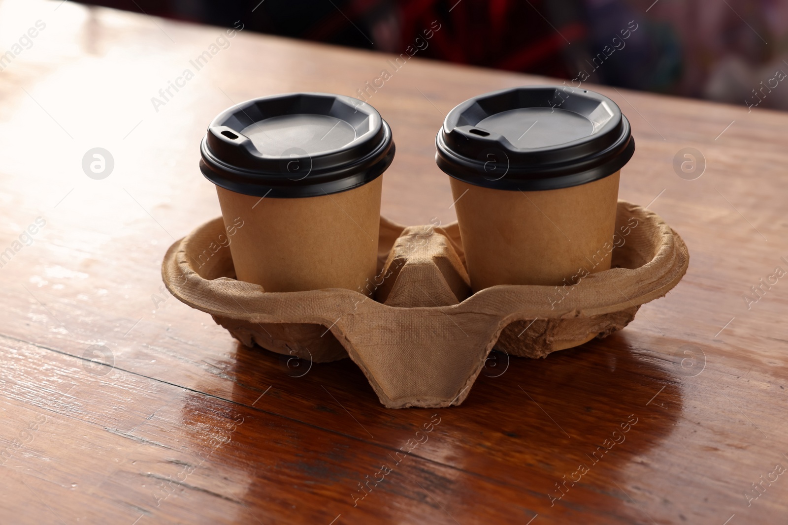 Photo of Paper coffee cups in carton holder on wooden table