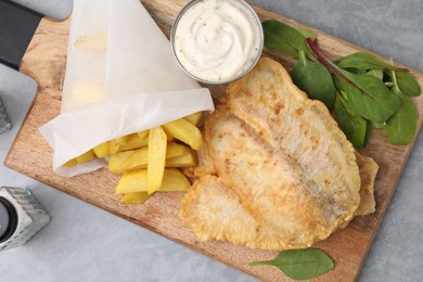 Delicious fish and chips with tasty sauce and mangold on gray table, top view